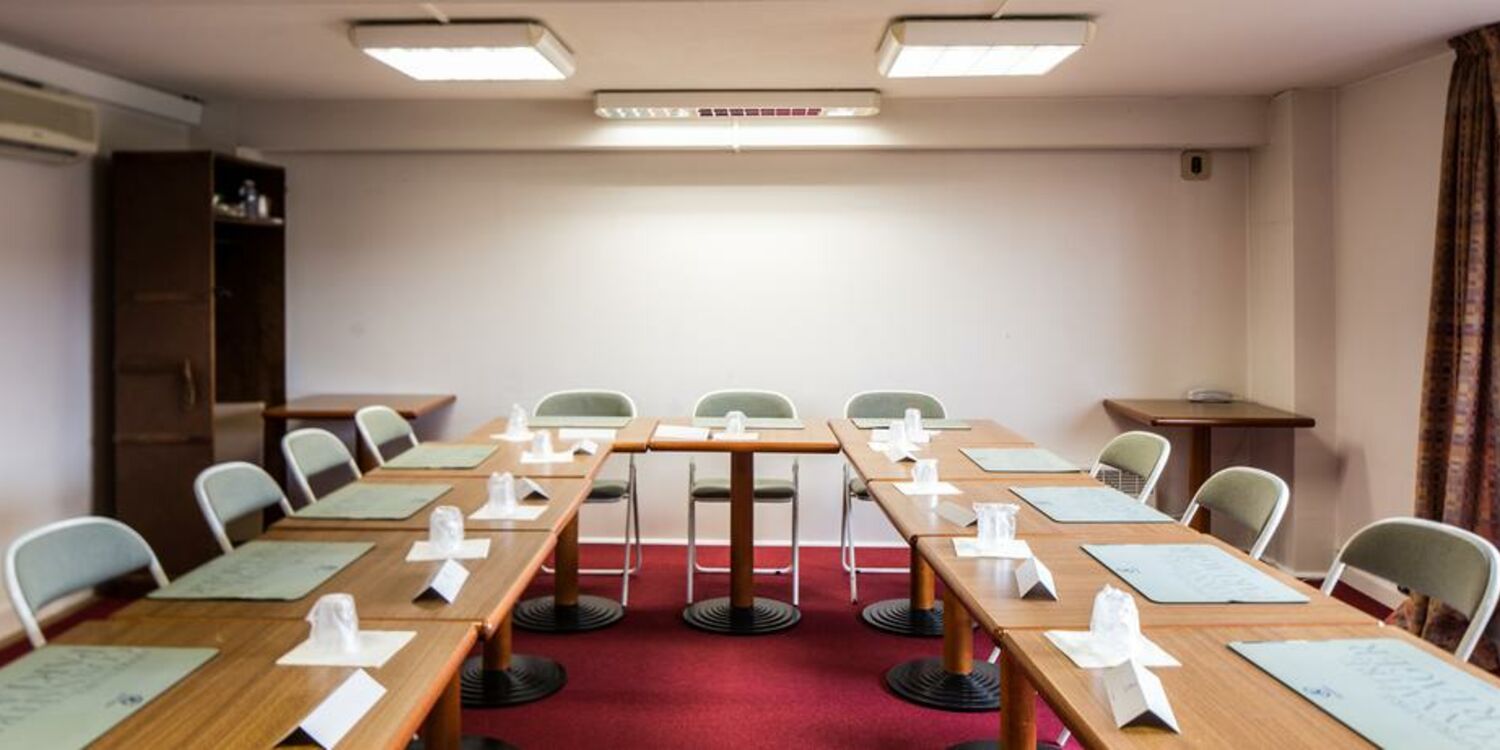 Salle de réunion en U avec tables, chaises et blocs-notes